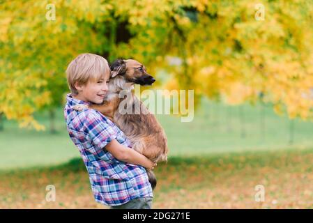 Garçon embrassant un chien et pleurs avec à l'automne, parc de la ville Banque D'Images