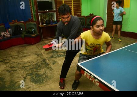 Kajol Dey, un joueur et entraîneur de tennis de table handicapé de 49 ans, est vu coacher une jeune fille dans son camp d'entraînement à l'occasion de la Journée internationale des personnes handicapées (IDPD). Agartala, Tripura, Inde. Banque D'Images