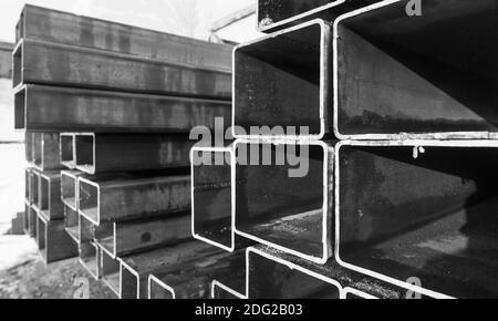 Pile de produits métalliques laminés, tuyaux en acier humide avec section transversale rectangulaire, photo en gros plan noir et blanc avec mise au point douce sélective Banque D'Images