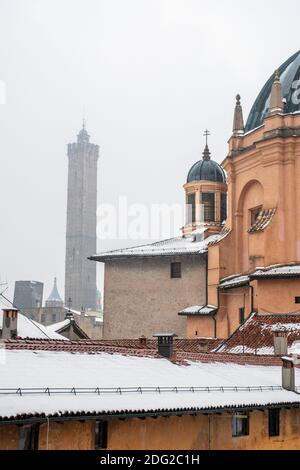 Vue sur les toits de neige tombant sur l'église Santa Maria Della Vita, Bologne, Italie, et les tours penchées de Garisenda et degli Asinelli. Banque D'Images