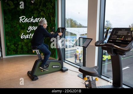 La photo du 2020 décembre montre un conducteur sur une moto d'exercice au premier piste électrique du Royaume-Uni à Braintree, dans l'Essex., qui aide à charger sa voiture. La première piste électrique du Royaume-Uni a ouvert ses portes aujourd’hui – avec la possibilité de charger des voitures en seulement 20 minutes. Le site de Braintree, dans l'Essex, est le premier d'environ 100 forecourts électriques construits dans tout le pays au cours des cinq prochaines années dans le cadre d'un programme de 1 milliard de livres sterling. Elle devait ouvrir en novembre, mais elle a été retardée en raison de la pandémie du coronavirus et du deuxième confinement national. Banque D'Images