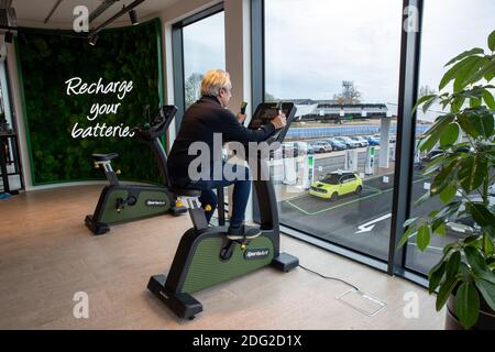 La photo du 2020 décembre montre un conducteur sur une moto d'exercice au premier piste électrique du Royaume-Uni à Braintree, dans l'Essex., qui aide à charger sa voiture. La première piste électrique du Royaume-Uni a ouvert ses portes aujourd’hui – avec la possibilité de charger des voitures en seulement 20 minutes. Le site de Braintree, dans l'Essex, est le premier d'environ 100 forecourts électriques construits dans tout le pays au cours des cinq prochaines années dans le cadre d'un programme de 1 milliard de livres sterling. Elle devait ouvrir en novembre, mais elle a été retardée en raison de la pandémie du coronavirus et du deuxième confinement national. Banque D'Images