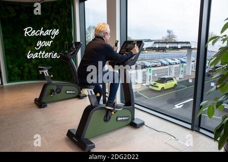 La photo du 2020 décembre montre un conducteur sur une moto d'exercice au premier piste électrique du Royaume-Uni à Braintree, dans l'Essex., qui aide à charger sa voiture. La première piste électrique du Royaume-Uni a ouvert ses portes aujourd’hui – avec la possibilité de charger des voitures en seulement 20 minutes. Le site de Braintree, dans l'Essex, est le premier d'environ 100 forecourts électriques construits dans tout le pays au cours des cinq prochaines années dans le cadre d'un programme de 1 milliard de livres sterling. Elle devait ouvrir en novembre, mais elle a été retardée en raison de la pandémie du coronavirus et du deuxième confinement national. Banque D'Images