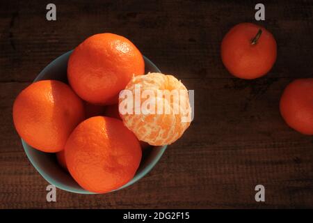 Encore la vie avec des mandarines sur fond de bois. Agrumes de clémentine dans un bol bleu. Banque D'Images