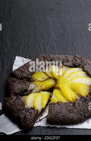 Tarte au chocolat avec poire pochée sur fond de pierre noire Banque D'Images