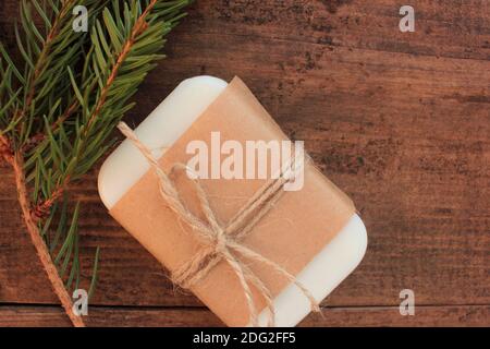 Barre de savon de conifère naturel fait main enveloppée de papier artisanal, et branche de sapin sur table en bois. Cadeau de Noël écologique. Banque D'Images