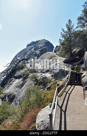 Moro Rock, une formation de roche en dôme de granit dans le parc national de Sequoia, Californie, États-Unis. Un visiteur masculin portant un cavalier vert commence la montée jusqu'au sommet. Banque D'Images