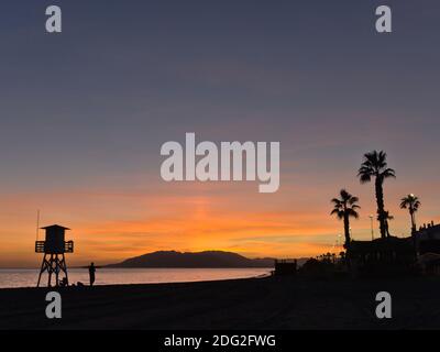 Silhouettes au coucher du soleil d'un poste de garde et palmiers la plage Banque D'Images