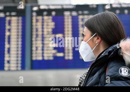 Voyages à thème en période de pandémie de corona. Jeune femme avec masque, masque à l'aéroport de Munich le 6 décembre 2020. Regarde le tableau de départ, le portrait, le portrait, le portrait. MODÈLE DISPONIBLE ! | utilisation dans le monde entier Banque D'Images