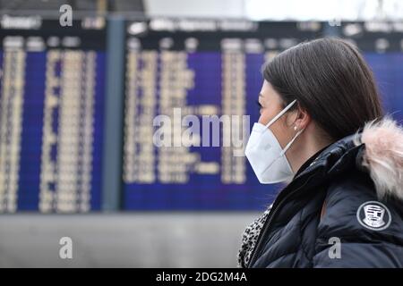 Voyages à thème en période de pandémie de corona. Jeune femme avec masque, masque à l'aéroport de Munich le 6 décembre 2020. Regarde le tableau de départ, le portrait, le portrait, le portrait. MODÈLE DISPONIBLE ! | utilisation dans le monde entier Banque D'Images