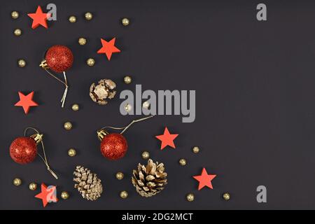 Décoration de Noël avec boules et étoiles élégantes en forme d'arbre rouge, cônes de sapin peints en or et petits boules de neige dorées sur fond noir foncé Banque D'Images
