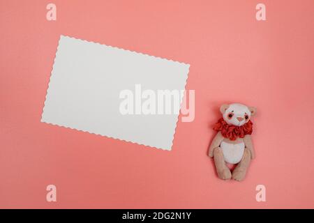 Carte postale blanche vierge et ours en peluche sur fond rose. Composition de Noël, nouvel an, Saint-Valentin, Journée internationale de la femme ou Fête des mères Banque D'Images