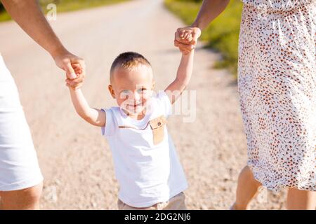 Bonne enfance d'un enfant avec maman et papa. L'enfant tient la main des parents. Banque D'Images