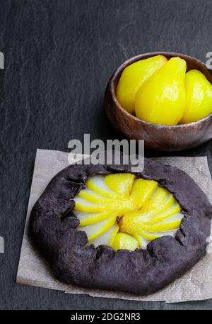 Tarte au chocolat avec poire pochée sur fond de pierre noire Banque D'Images