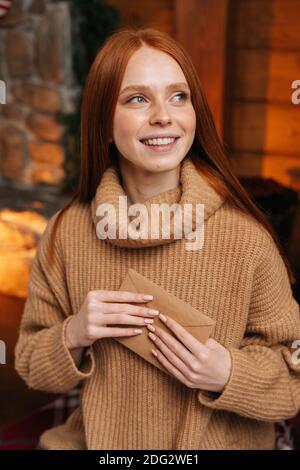 Gros plan d'une jeune femme souriante tenant doucement la main à proximité Carte de Noël coeur à l'aimé Banque D'Images