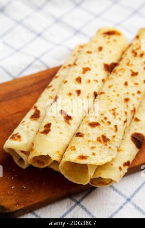 Pain plat de pommes de terre norvégien (Lefse) fait maison avec beurre et sucre sur un panneau rustique en bois sur tissu, vue à angle bas. Banque D'Images