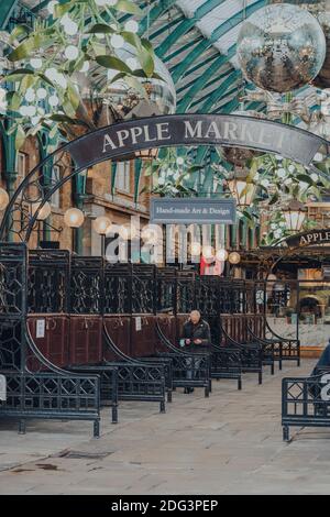 Londres, Royaume-Uni - 19 novembre 2020: Homme assis et utilisant son téléphone parmi les stands fermés dans Covent Garden Market, un des sites touristiques les plus populaires i Banque D'Images
