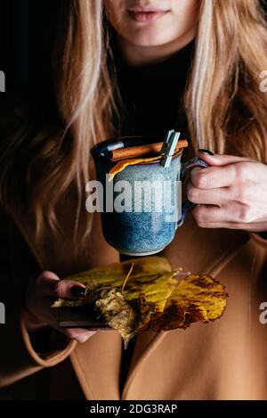 tasses de vin chaud dans les mains d'une fille dans un manteau d'automne Banque D'Images