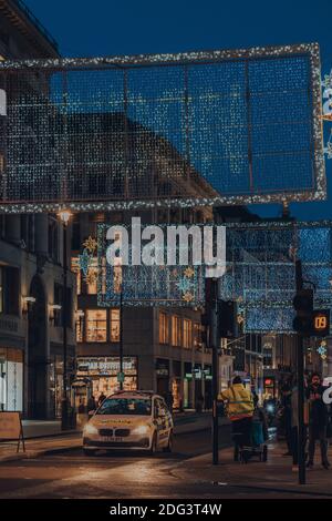 Londres, Royaume-Uni - 19 novembre 2020 : une voiture de police attend le soir une lumière rouge sous les feux de Noël sur Oxford Street. Oxford Street est une grande boutique Banque D'Images