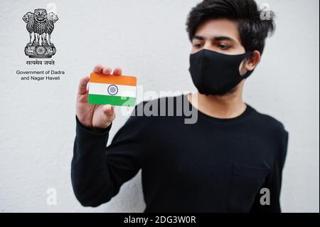 L'homme indien porte tout noir et masque facial, tenez le drapeau de l'Inde à la main isolé sur fond blanc avec Dadra Nagar Haveli Daman et DIU Union Territory em Banque D'Images