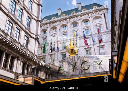 The Savoy Hotel, Londres, Angleterre, Royaume-Uni. Statue dorée de Pierre II Comte de Savoie à côté des drapeaux au-dessus de l'entrée du célèbre hôtel de luxe 5 étoiles. Banque D'Images