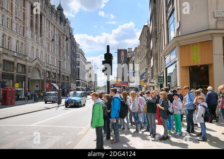 Un groupe surveillé de jeunes touristes européens adolescents attendant de traverser la route aux feux de signalisation sur le Strand dans le centre de Londres, Angleterre, Royaume-Uni Banque D'Images