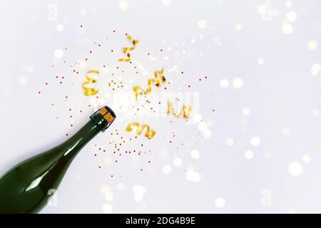 Bannière avec bouteille de champagne avec confettis et lumières sur fond blanc. Concept de Noël, d'anniversaire, de fête ou de mariage. Espace de copie de la vue de dessus Banque D'Images