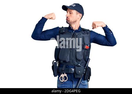 Jeune homme beau portant l'uniforme de police montrant les bras muscles souriant fier. Concept de forme physique. Banque D'Images