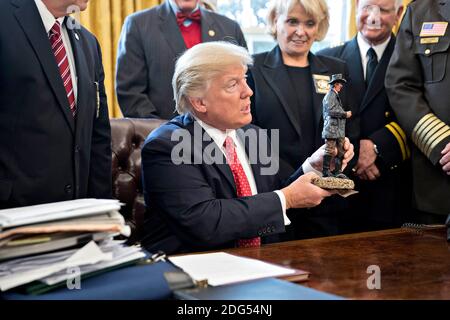 Le président américain Donald Trump tient une statue qu'il a reçue en cadeau lors d'une rencontre avec des sheriffs du comté dans le bureau ovale de la Maison Blanche à Washington, D.C., aux États-Unis, le mardi 7 février 2017. L'administration Trump retournera mardi devant les tribunaux pour soutenir qu'elle dispose d'une large autorité en matière de sécurité nationale et pour exiger le rétablissement d'une interdiction de voyager sur sept pays à majorité musulmane qui ont bloqué les réfugiés, déclenché des protestations et remis au jeune gouvernement son premier test crucial. Photographe: Andrew Harrer/Pool/ABACAPRESS.COM Banque D'Images