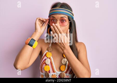 Belle femme hispanique portant le style bohème et hippie couvrant la bouche avec la main, choquée et peur pour l'erreur. Expression surprise Banque D'Images