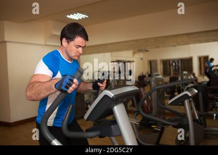 L'exercice de l'homme sur la machine elliptique en salle de sport Banque D'Images