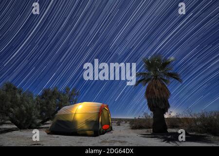 Tente de camping illuminée sous une pleine lune et des sentiers étoiles Banque D'Images