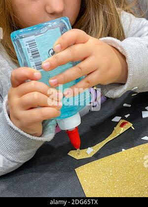 Gros plan des mains de la fille en utilisant la colle d'artisanat Banque D'Images