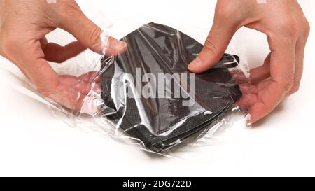 Paquet KN-95 protection masques médicaux en noir dans les mains de femme sur fond blanc. Prévention de la propagation du virus et de l'épidémie, protection Banque D'Images