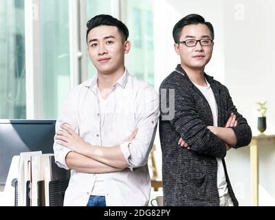 portrait de deux jeunes entrepreneurs asiatiques debout dos à dos au bureau Banque D'Images