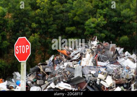 Un panneau d'arrêt rouge envoie un message tel qu'il est placé devant une grande pile de déchets métalliques Banque D'Images