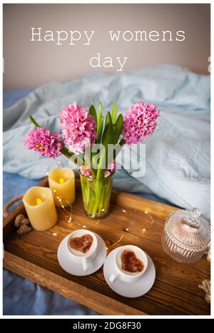 Carte de voeux Journée internationale de la femme le 8 mars. Surprise, petit déjeuner au lit, deux tasses de cappuccino avec un coeur au milieu, belles fleurs de h Banque D'Images