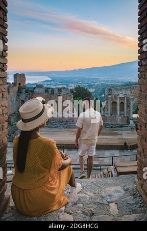 Taormina Sicile, couple regardant le coucher du soleil sur les ruines de l'ancien théâtre grec de Taormina, Sicile. Couple mi-âge sur les vacances Sicilia Banque D'Images