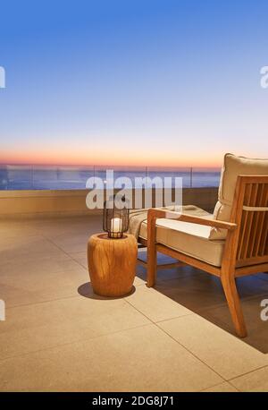 Lanterne et table d'extérieur sur un patio luxueux avec coucher de soleil sur l'océan vue Banque D'Images