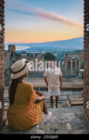 Taormina Sicile, couple regardant le coucher du soleil sur les ruines de l'ancien théâtre grec de Taormina, Sicile. Couple mi-âge sur les vacances Sicilia Banque D'Images