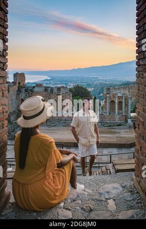 Taormina Sicile, couple regardant le coucher du soleil sur les ruines de l'ancien théâtre grec de Taormina, Sicile. Couple mi-âge sur les vacances Sicilia Banque D'Images