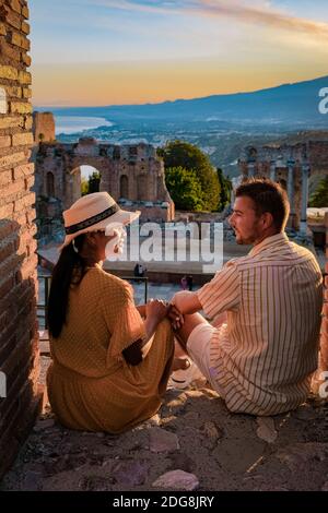 Taormina Sicile, couple regardant le coucher du soleil sur les ruines de l'ancien théâtre grec de Taormina, Sicile. Couple mi-âge sur les vacances Sicilia Banque D'Images