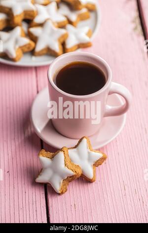 Le glaçage des étoiles de pain d'épice. Biscuits de Noël traditionnels et tasse de café sur table en bois rose. Banque D'Images