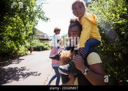Portrait un père heureux portant des filles sur un trottoir ensoleillé Banque D'Images