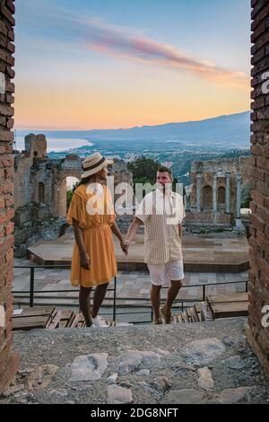 Taormina Sicile, couple regardant le coucher du soleil sur les ruines de l'ancien théâtre grec de Taormina, Sicile. Couple mi-âge sur les vacances Sicilia Banque D'Images