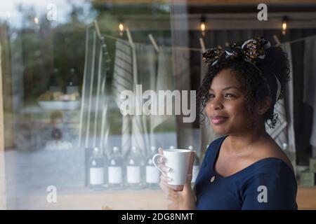 Une femme attentionnés qui boit du café à la fenêtre du magasin Banque D'Images