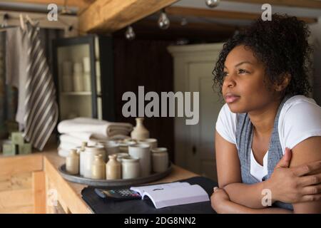 Une femme propriétaire de boutique attentionnés au comptoir, qui a une vue sur l'extérieur en prévision Banque D'Images