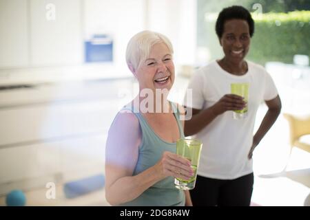 Des femmes âgées heureuses et amies buvant de l'eau après avoir fait de l'exercice à la maison Banque D'Images