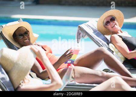 Des femmes heureuses et des amis seniors se baignant au soleil au bord de la piscine en été Banque D'Images