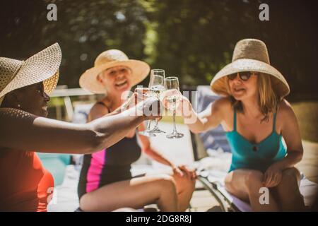 Des femmes âgées, amis, buvant du champagne à la piscine en été Banque D'Images